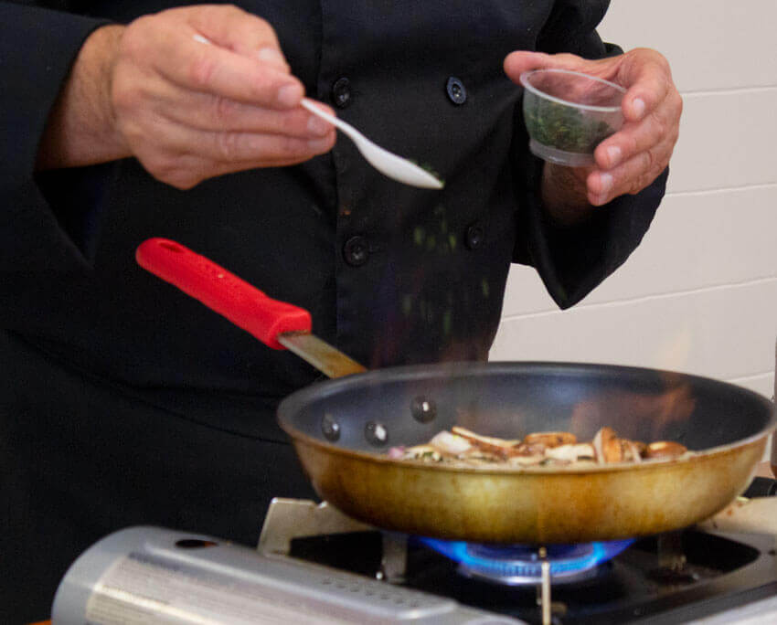 Chef sprinkles herbs over mushroom sauce