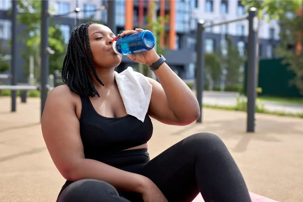 Woman drinking water while exercising