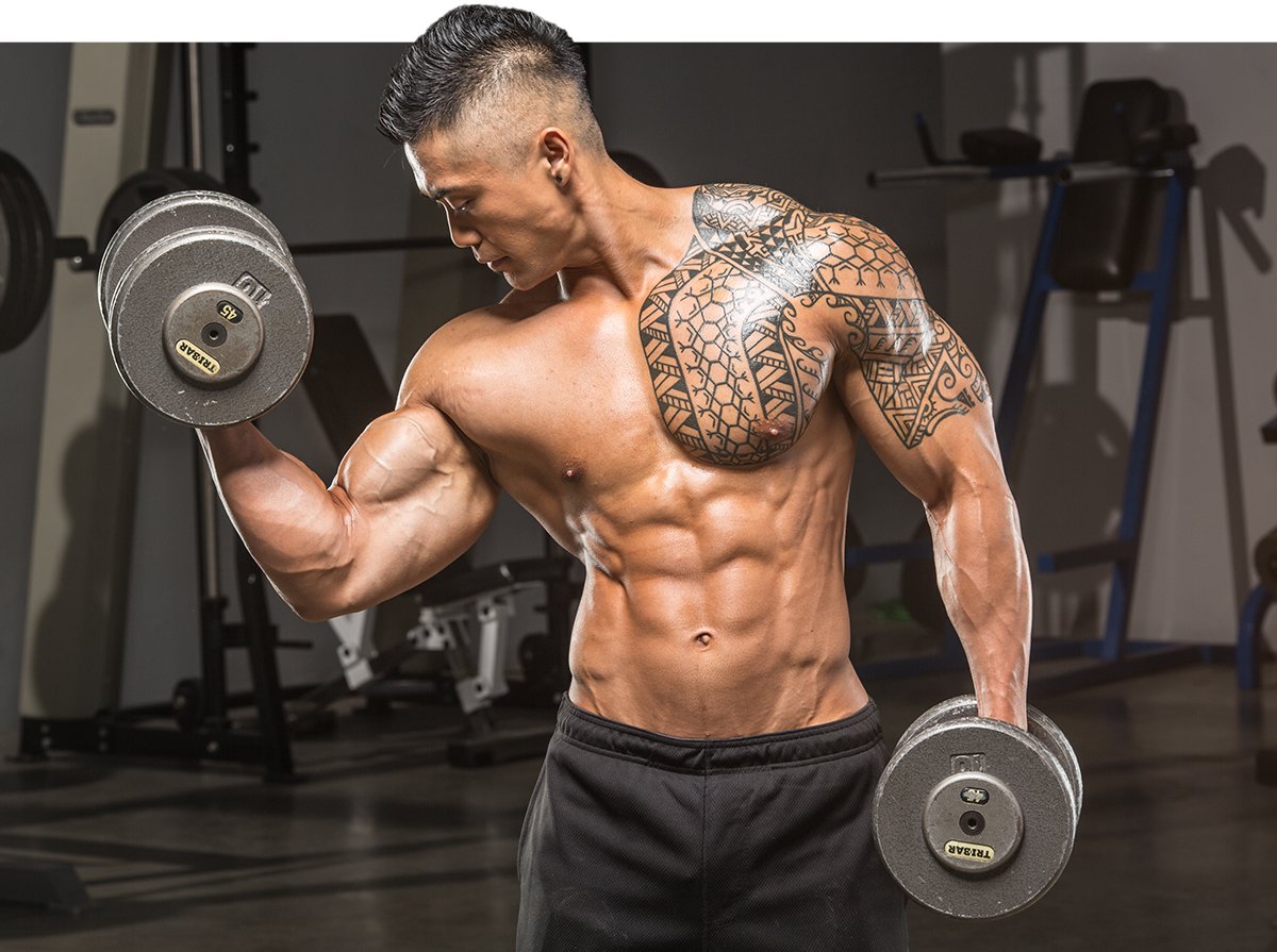 Tattooed man lifting dumbbells