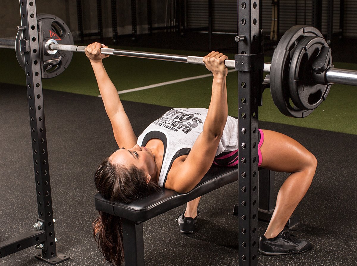 Woman bench pressing with barbell