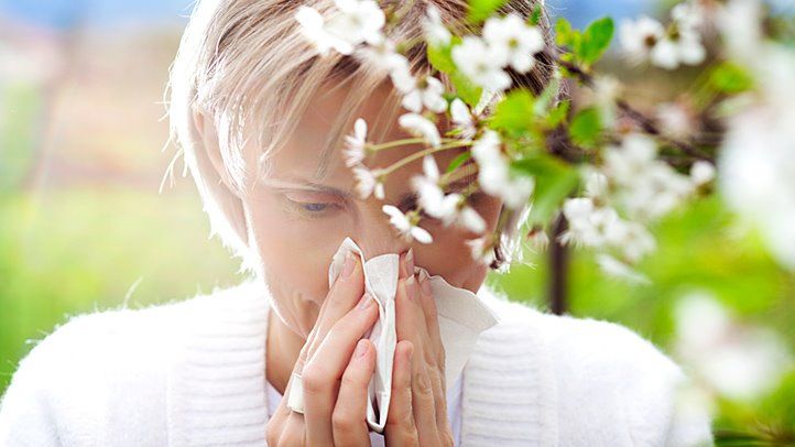 Woman blowing nose outdoors