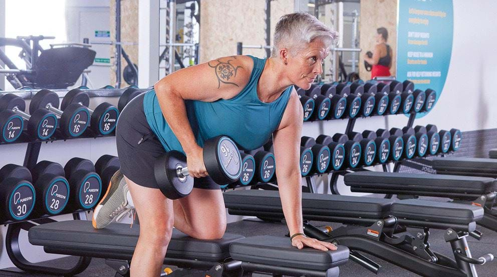 Woman doing barbell squats in gym