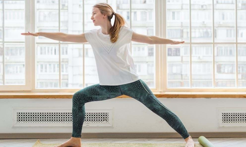 Pregnant woman stretching on mat indoors