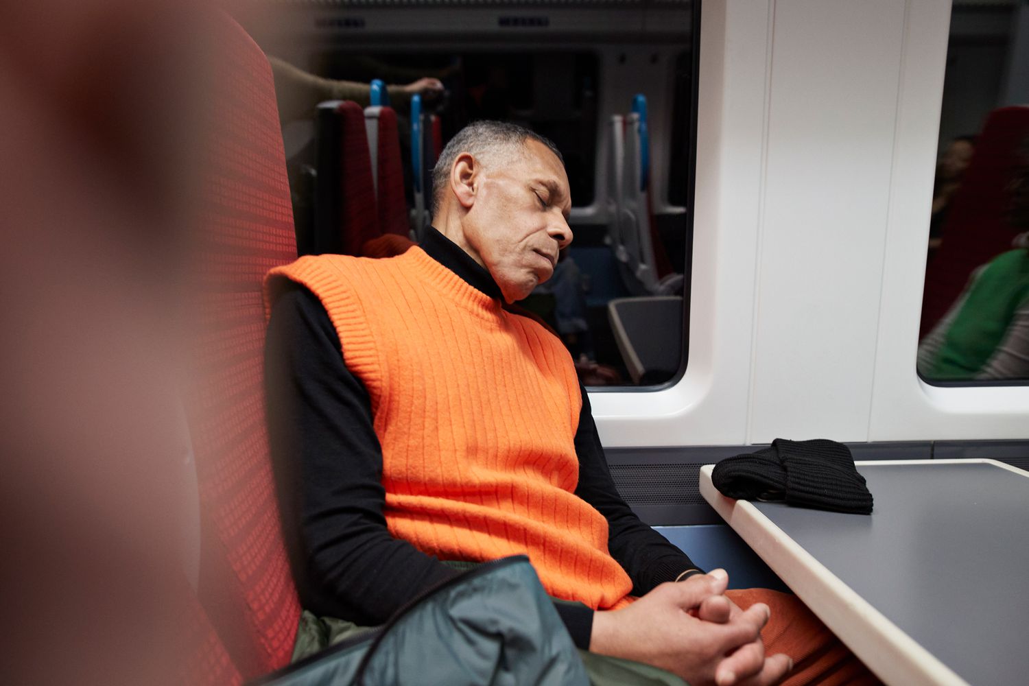 Businessman asleep on train seat