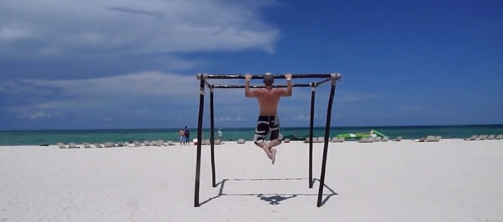 Man performs pull-up on sunny beach