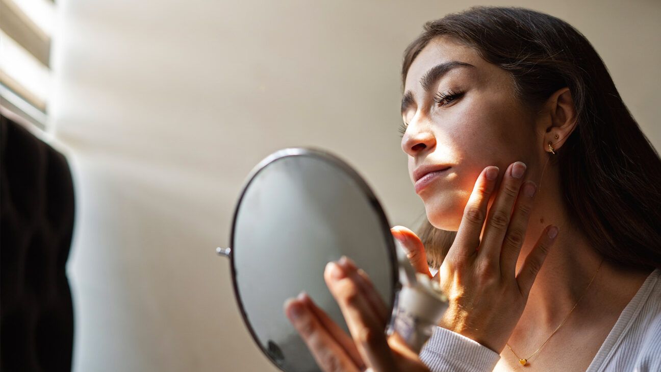 Woman applying moisturizer to face