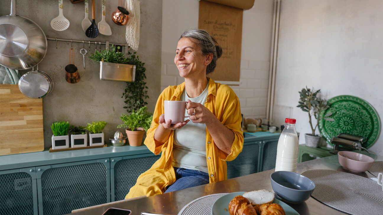 Mature woman sips coffee smiling