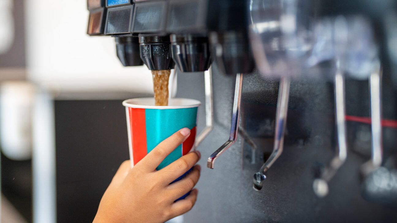 Hand filling cup at soda dispenser