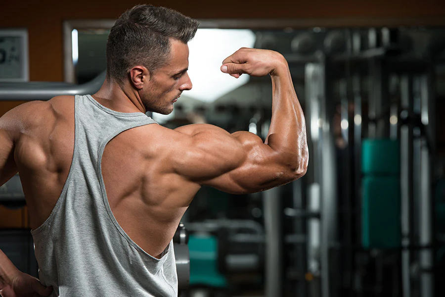 Man flexing bicep at gym