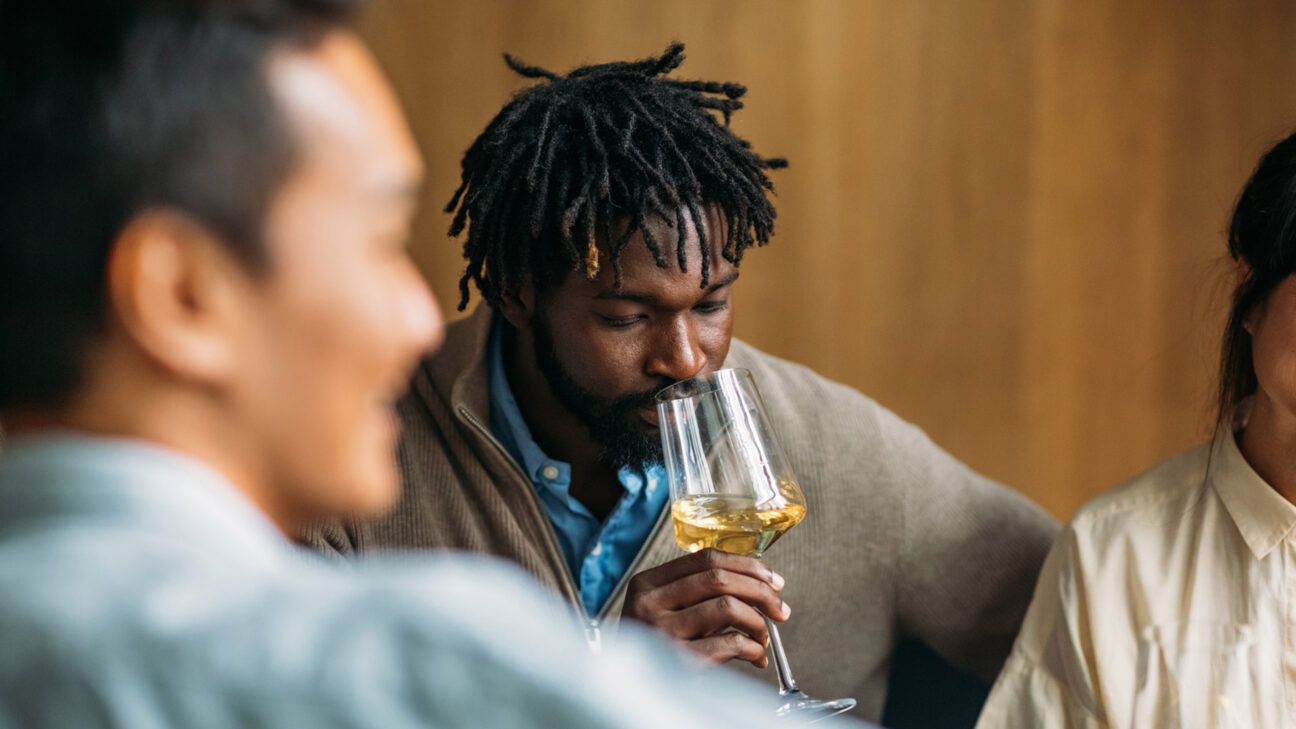 Man sips from white wine glass