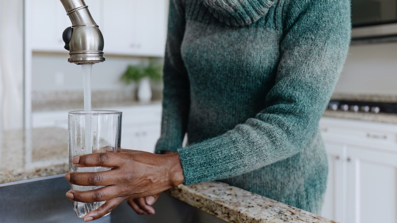 Woman pouring tap water into cup