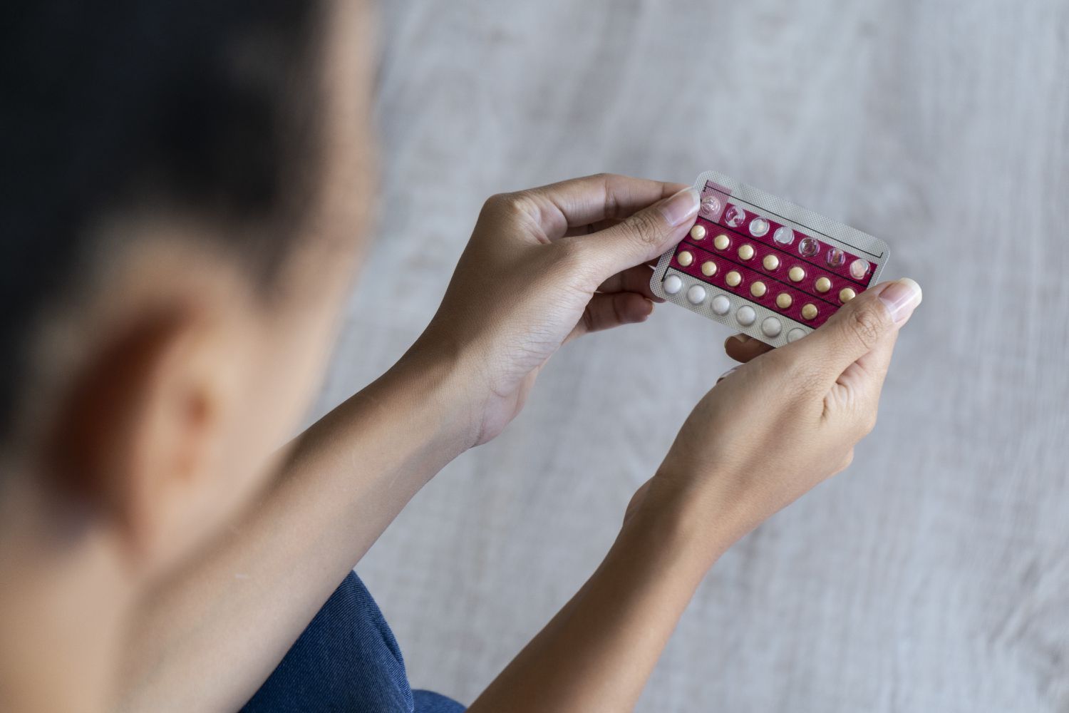 Hand holding pink birth control packet