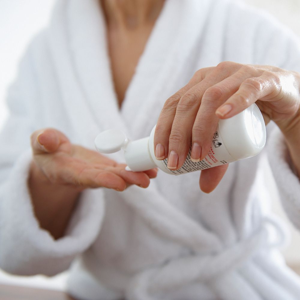 Woman applying face moisturizer