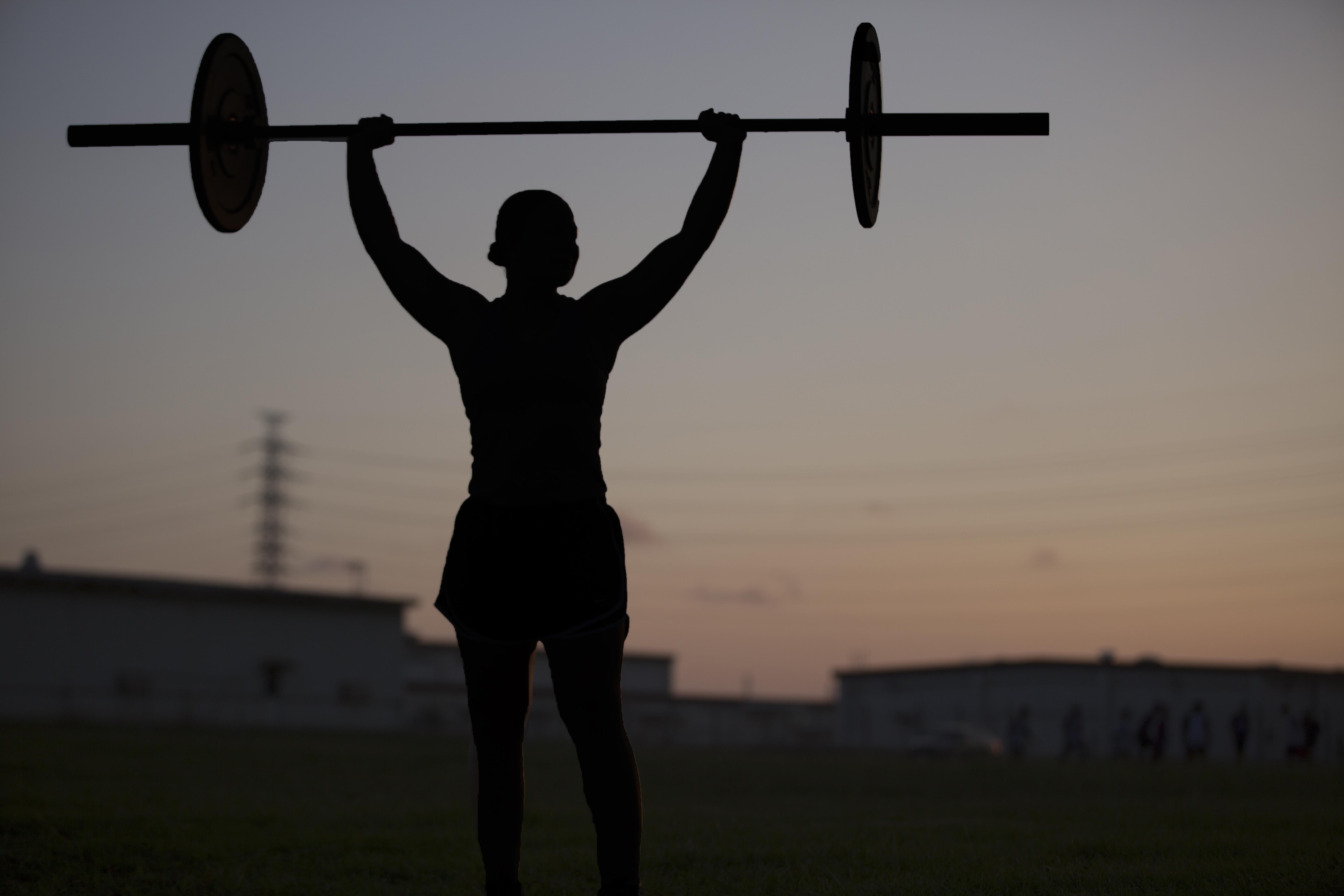 Person doing overhead press at dusk