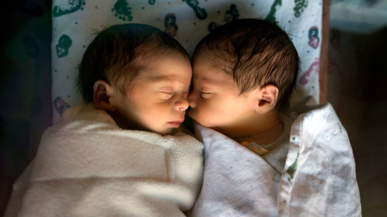 Sleeping twins in matching white outfits