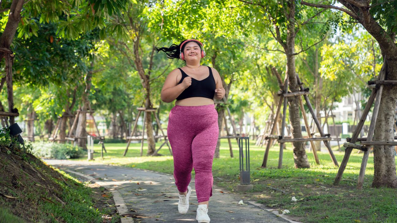 Woman jogging through tree-lined path