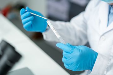 Scientist examining clear liquid in tube