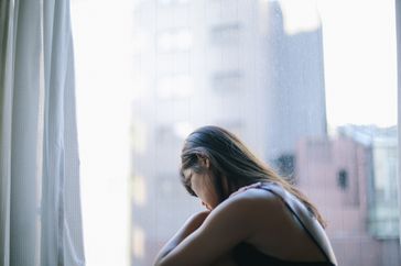 Woman stares pensively through window