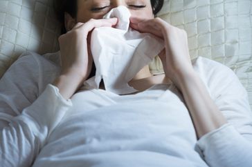 Woman lying in bed with tissue