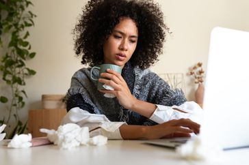 Woman working with laptop drinking tea