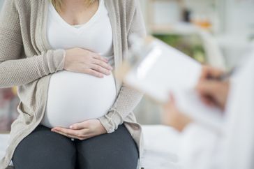 Pregnant woman's bare belly against white