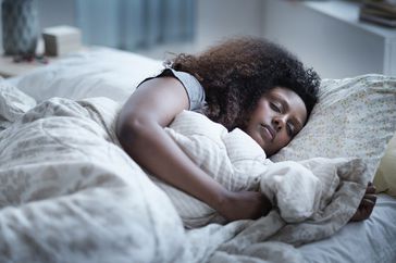 Woman sleeping peacefully under white bedding